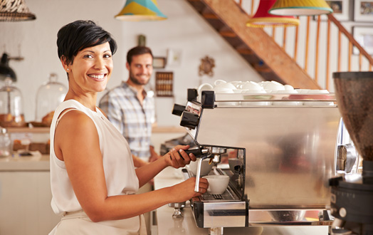 woman smiling while making a cup of coffee