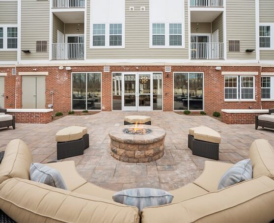 Outside apartment courtyard area with lit firepit and couches