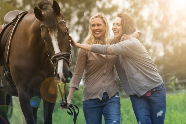 a mother and daughter petting a horse on a farm